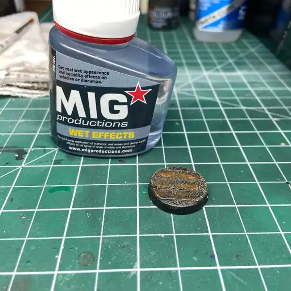 Wet looking Warhammer base, after applying MIG Wet Effects, on top of a hobby cutting mat